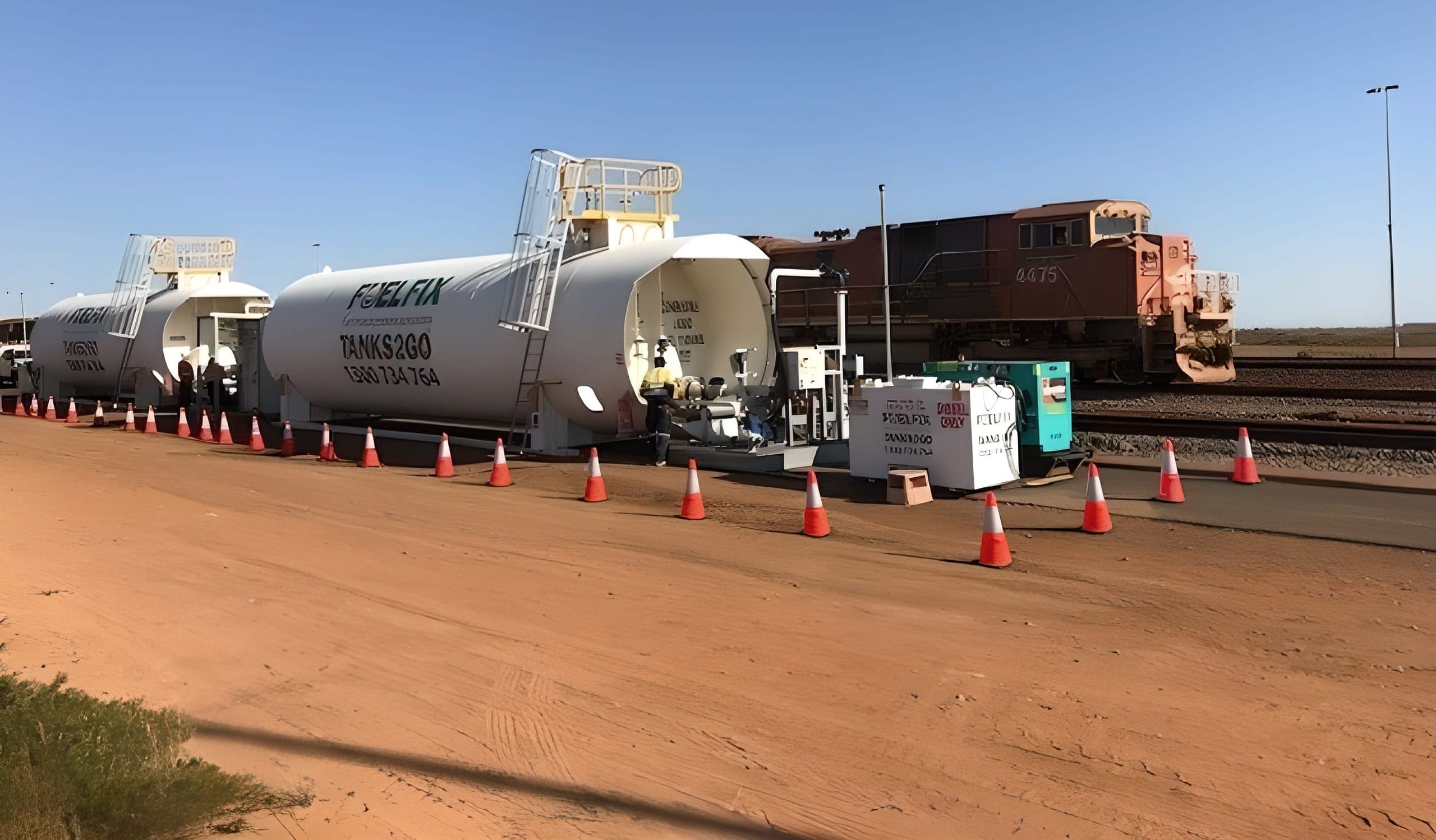 Bulk fuel storage tanks positioned alongside rail infrastructure, illustrating fuel supply chain dependency and disruption risk